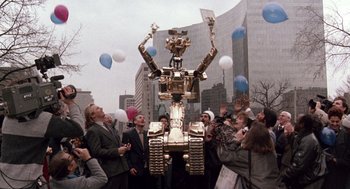 Movie still from “Short Circuit 2” (1988), directed by Kenneth Johnson – A crowd of people standing next to a large robot; Extreme Wide shot, Low angle