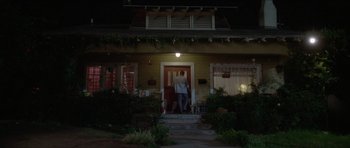 Movie still from “Short Cuts” (1993), directed by Robert Altman – A man standing on the front steps of a house at night; Extreme Wide shot, Low angle