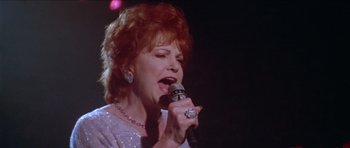 Movie still from “Short Cuts” (1993), directed by Robert Altman – An older woman is singing into a microphone; Close Up shot, Low angle