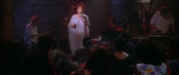 Movie still from “Short Cuts” (1993), directed by Robert Altman – An older woman is singing in front of an audience; Wide shot, High angle