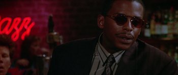 Movie still from “Short Cuts” (1993), directed by Robert Altman – A person wearing a suit and sunglasses; Close Up shot, Low angle