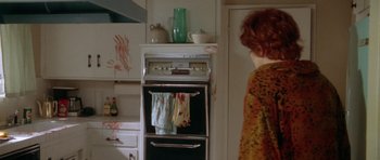 Movie still from “Short Cuts” (1993), directed by Robert Altman – A woman standing next to a stove in a kitchen; Medium shot, High angle