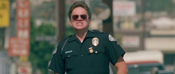 Movie still from “Short Cuts” (1993), directed by Robert Altman – A man in a police officer's uniform with sunglasses on; Close Up shot, Low angle