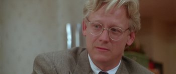 Movie still from “Short Cuts” (1993), directed by Robert Altman – A person wearing a suit and glasses; Close Up shot, Over the shoulder angle