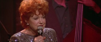 Movie still from “Short Cuts” (1993), directed by Robert Altman – An older woman with red hair is holding a microphone; Close Up shot, High angle