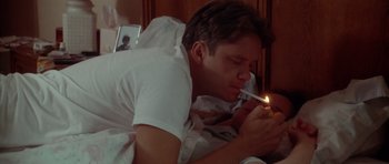 Movie still from “Short Cuts” (1993), directed by Robert Altman – A man laying in a bed with a lit candle in his mouth; Close Up shot, High angle