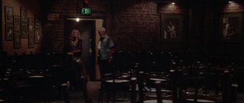 Movie still from “Short Cuts” (1993), directed by Robert Altman – A man and a woman standing in front of chairs in a room; Wide shot, Over the shoulder angle