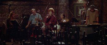 Movie still from “Short Cuts” (1993), directed by Robert Altman – A group of people sitting in chairs with instruments; Wide shot, High angle