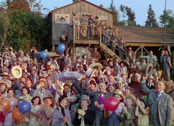 Movie still from “Show Boat” (1951), directed by George Sidney – A crowd of people standing in front of a building; Extreme Wide shot, High angle
