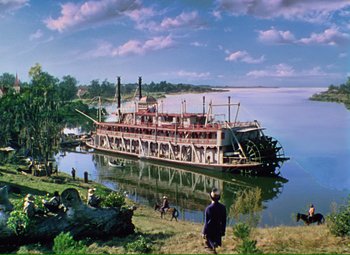 Movie still from “Show Boat” (1951), directed by George Sidney – A boat is docked in a body of water; Extreme Wide shot, Low angle