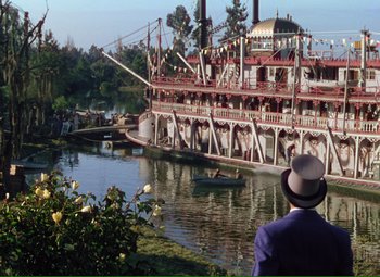 Movie still from “Show Boat” (1951), directed by George Sidney – A man standing in front of a boat on a river; Extreme Wide shot, High angle
