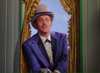 Movie still from “Show Boat” (1951), directed by George Sidney – A man wearing a purple suit and a top hat in front of a window; Medium shot, Low angle