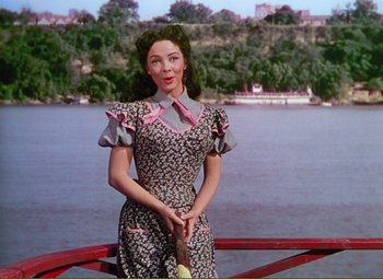 Movie still from “Show Boat” (1951), directed by George Sidney – A woman standing on a bridge near a body of water; Medium shot, Low angle