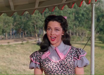 Movie still from “Show Boat” (1951), directed by George Sidney – A woman in a dress and a pink bow tie; Medium shot, Low angle