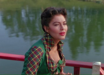 Movie still from “Show Boat” (1951), directed by George Sidney – A woman sitting on a railing next to a body of water; Medium shot, Over the shoulder angle