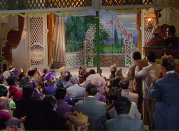 Movie still from “Show Boat” (1951), directed by George Sidney – A group of people sitting in front of a stage; Extreme Wide shot, High angle