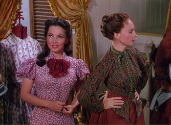 Movie still from “Show Boat” (1951), directed by George Sidney – Two women standing next to each other in front of a window; Medium shot, Over the shoulder angle