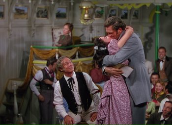 Movie still from “Show Boat” (1951), directed by George Sidney – A couple of people that are hugging in a room; Wide shot, Over the shoulder angle