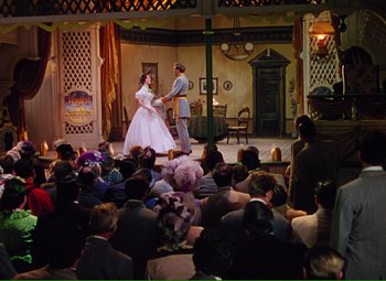 Movie still from “Show Boat” (1951), directed by George Sidney – A crowd of people watching a performance of a play; Wide shot, High angle