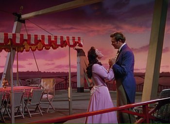 Movie still from “Show Boat” (1951), directed by George Sidney – A man and a woman standing next to each other; Wide shot, Low angle