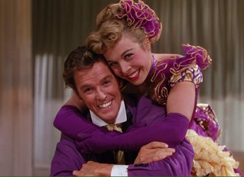 Movie still from “Show Boat” (1951), directed by George Sidney – A man and a woman hugging each other in purple; Medium shot, Low angle