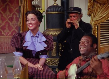 Movie still from “Show Boat” (1951), directed by George Sidney – A woman sitting next to a man and a man holding a guitar; Medium shot, Over the shoulder angle