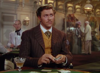 Movie still from “Show Boat” (1951), directed by George Sidney – A man sitting at a table in front of cards; Medium shot, Over the shoulder angle