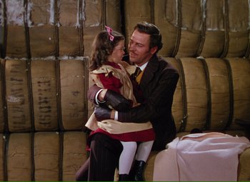 Movie still from “Show Boat” (1951), directed by George Sidney – A man and a little girl sitting on the lap of each other; Medium shot, High angle