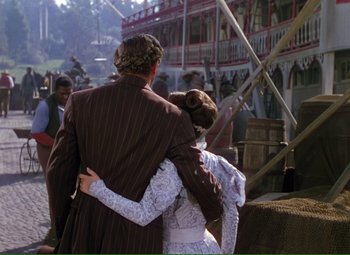 Movie still from “Show Boat” (1951), directed by George Sidney – A man and a woman are holding each other in front of a crowd of onlookers; Wide shot, Over the shoulder angle