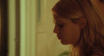 A young blonde woman looking down at her face