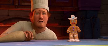Movie still from “Shrek Forever After” (2010), directed by Mike Mitchell – A man in a chef's hat looks at a gingerbread man; Close Up shot, Over the shoulder angle
