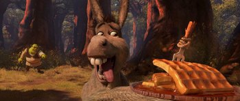 Movie still from “Shrek Forever After” (2010), directed by Mike Mitchell – A donkey with its tongue hanging out sitting in front of a plate of food; Medium shot, High angle