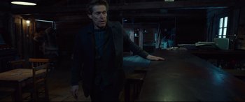 Movie still from “Siberia” (2020), directed by Abel Ferrara – A man standing in a dark room with his hand outstretched; Medium shot, Low angle