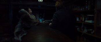 Movie still from “Siberia” (2020), directed by Abel Ferrara – Two people sitting at a table in a dark room; Medium shot, Over the shoulder angle