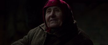 Movie still from “Siberia” (2020), directed by Abel Ferrara – An old woman wearing a red hat and a brown coat; Close Up shot, Over the shoulder angle