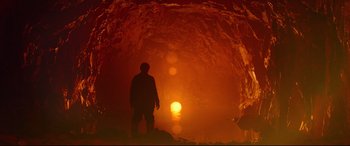 Movie still from “Siberia” (2020), directed by Abel Ferrara – A man standing in front of an orange light in a cave; Wide shot, Low angle