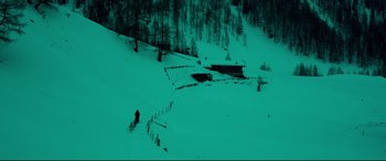 Movie still from “Siberia” (2020), directed by Abel Ferrara – A person riding skis down a snow covered slope; Extreme Wide shot, High angle