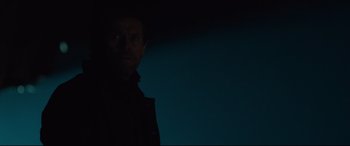 Movie still from “Siberia” (2020), directed by Abel Ferrara – A man standing in the dark with his head turned to the side; Close Up shot, Low angle