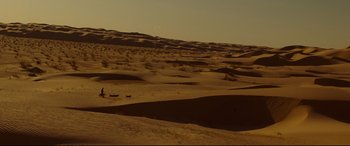 Movie still from “Siberia” (2020), directed by Abel Ferrara – A person walking a dog in the desert; Extreme Wide shot, High angle