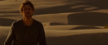 Movie still from “Siberia” (2020), directed by Abel Ferrara – A man standing in front of a desert landscape; Medium shot, Over the shoulder angle