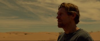 Movie still from “Siberia” (2020), directed by Abel Ferrara – A person in a field with a sky in the background; Close Up shot, Over the shoulder angle