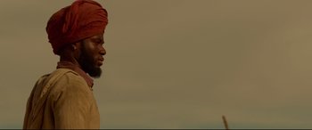Movie still from “Siberia” (2020), directed by Abel Ferrara – A man with a beard wearing a red turban; Close Up shot, Low angle