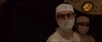 Movie still from “Siberia” (2020), directed by Abel Ferrara – A man wearing a surgical mask and a white gown; Close Up shot, Low angle