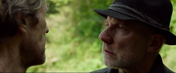 Movie still from “Siberia” (2020), directed by Abel Ferrara – A person wearing a hat and looking to the side; Close Up shot, Over the shoulder angle