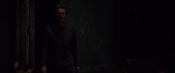 Movie still from “Siberia” (2020), directed by Abel Ferrara – A man standing in the dark in a dark room; Medium shot, Over the shoulder angle