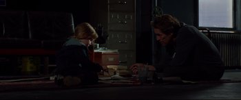Movie still from “Siberia” (2020), directed by Abel Ferrara – Two people sitting at a table in a dark room; Medium shot, High angle