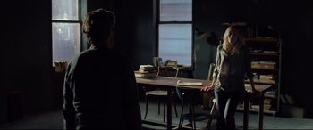 Movie still from “Siberia” (2020), directed by Abel Ferrara – Two people sitting at a table in a dark room; Wide shot, Over the shoulder angle