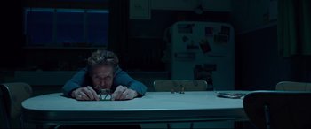 Movie still from “Siberia” (2020), directed by Abel Ferrara – A person sitting at a table with a toy; Medium shot, High angle