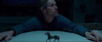 Movie still from “Siberia” (2020), directed by Abel Ferrara – A man sitting at a table with a toy horse in front of him; Close Up shot, Low angle