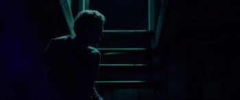 Movie still from “Siberia” (2020), directed by Abel Ferrara – A man sitting on the stairs in the dark; Medium shot, Low angle